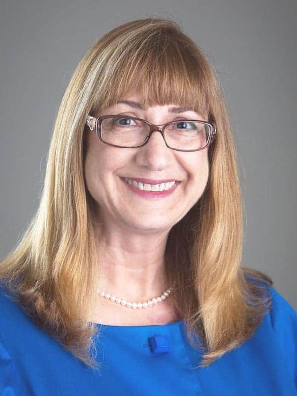 Smiling woman with glasses and blonde hair in a blue top, representing The Arc of Ventura County.